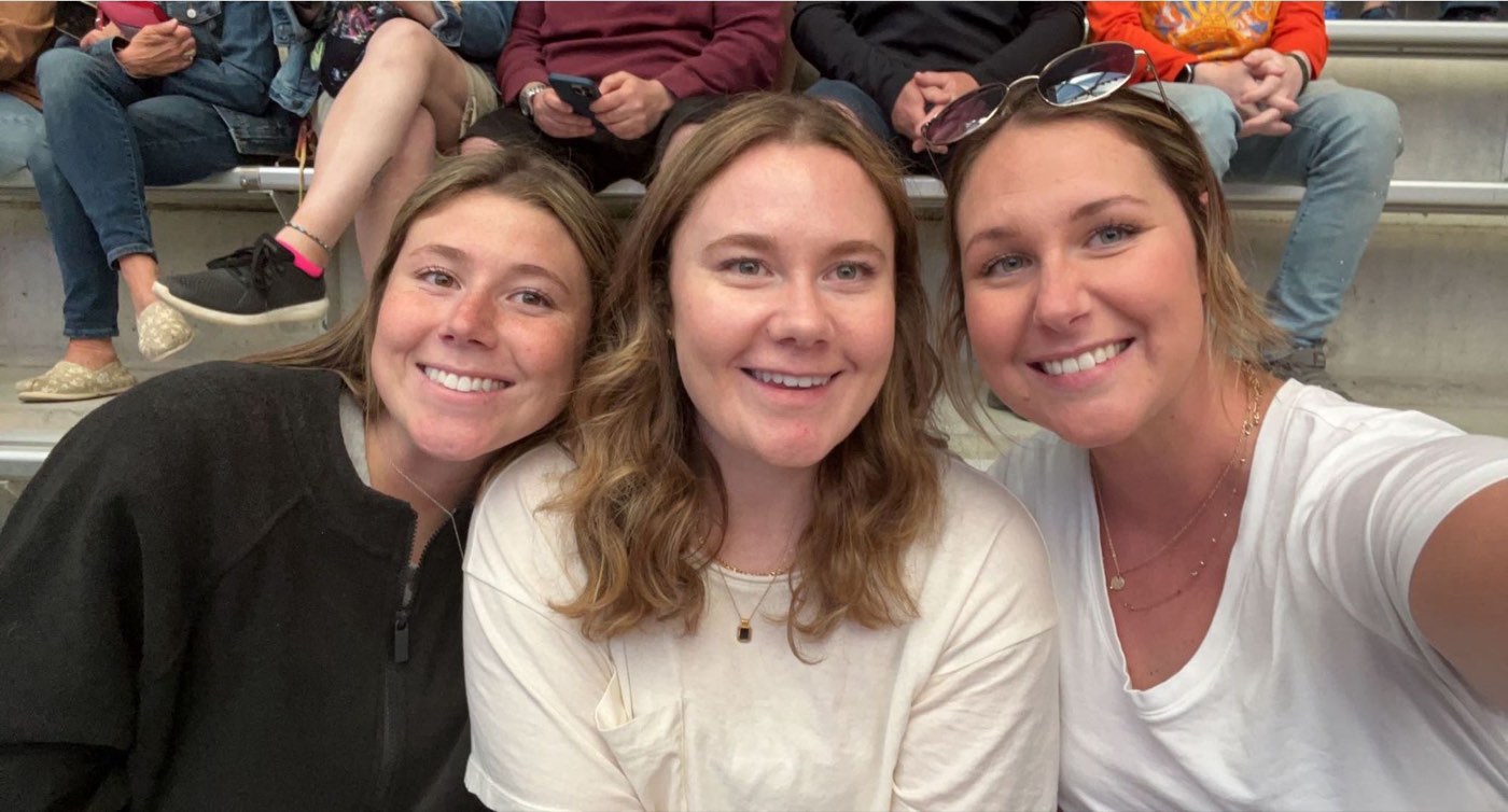Three friends in the bleachers at a game